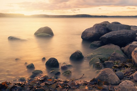 Long exposure landscape with stones in water over autumn sunsetの写真素材
