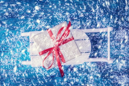 Gift box on wooden sled over snowbound backgroundの写真素材