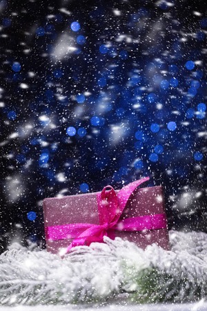 Gift box in snowfall over blue holiday backgroundの写真素材