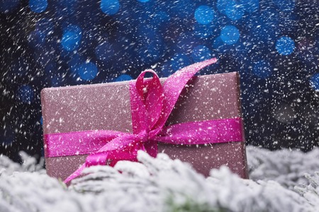 Gift box in snowfall over blue defocused lightsの写真素材