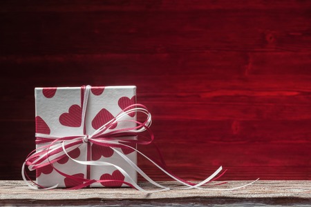 Gift box over red wooden background on Valentines dayの写真素材