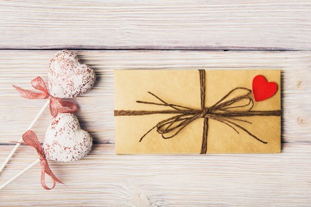 Love letter and decorative hearts over wooden background