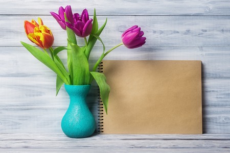 Still life with tulips in vase and blank paper sheetの写真素材