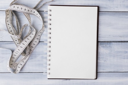 Mockup of note pad with measuring tape over light wooden backgroundの写真素材