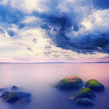 Landscape with stones in water over stormy skyの写真素材