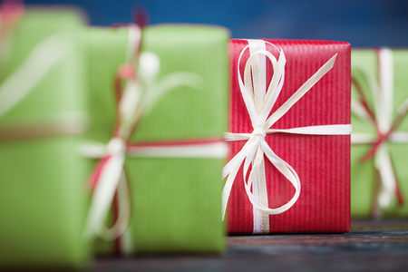 One red gift box among green, focus on redの写真素材