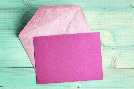 Top view of blank pink card and envelopes on light green wooden backgroundの写真素材