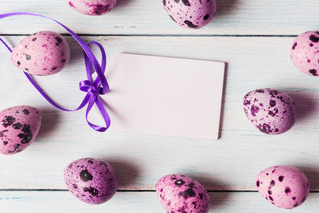 Pink painted eggs with white tag on wooden background.の写真素材