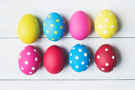Multicolored Easter eggs over white wooden background.の写真素材