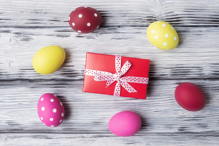 Painted Easter eggs and gift box over rustic wooden background.の写真素材