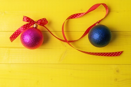 Christmas balls with long curly ribbon on yellowの写真素材