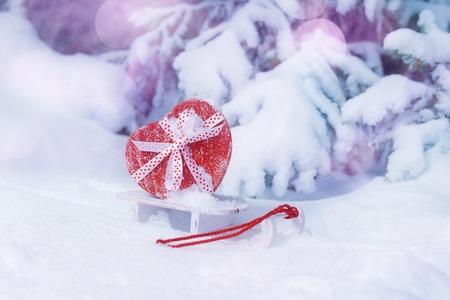 Heart shaped red gift box on sleigh in snowy winter forest. Valentines day conceptの写真素材