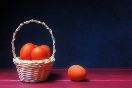 Orange easter eggs in basket over blue stone  with copy spaceの写真素材