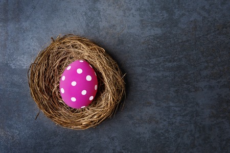 Pink Easter egg in nest over dark stoneの写真素材