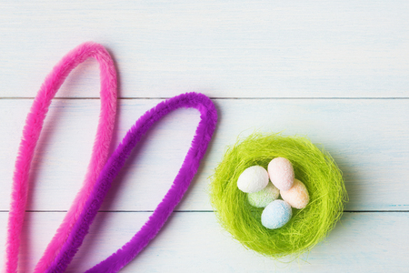 Bunny ears and decorative eggs in nest over woodenの写真素材