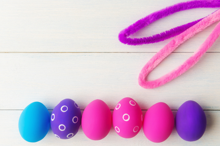 Bunny ears and decorative pink and purple eggs on wooden  with copy spaceの写真素材