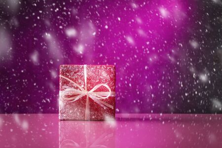 Red gift box in snow over violetの写真素材