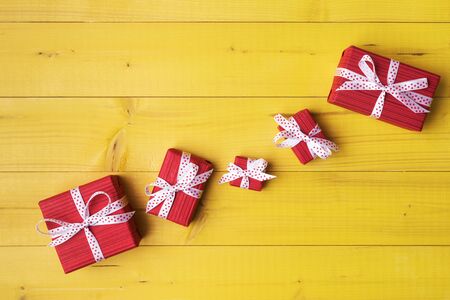 Set of similar red gift boxes on yellow wooden