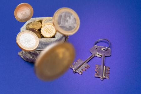 Euro coins in bag and key to the house on blueの写真素材