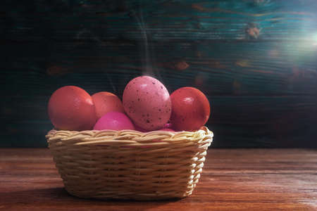 Easter boiled eggs in basket over dark wooden background