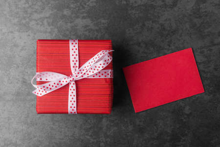 Red gift box with blank card over dark stone backgroundの写真素材