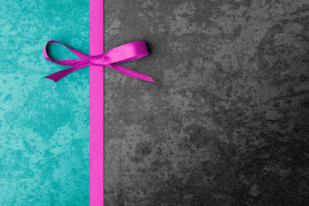 Decorative violet bow and ribbon on texture dark background with copy spaceの写真素材