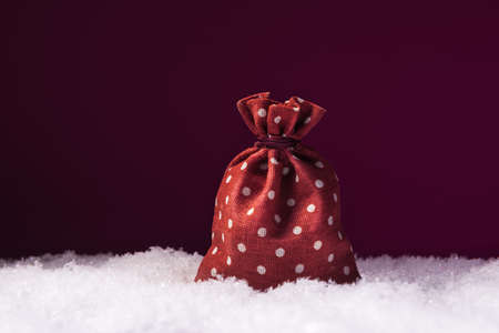 Christmas concept with Santa gift bag in snow over dark pink background with copy spaceの写真素材