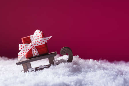 Santa's sleigh with red gift box in snow over pink background with copy space. Christmas and New Year conceptの写真素材