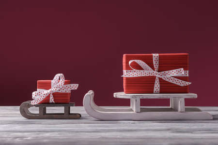 Big and small red gifts on Santa sleight over dark pink background. Christmas and New Year holiday greetingの写真素材