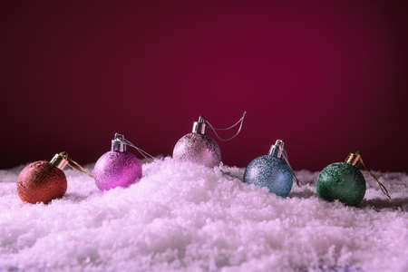 Christmas baubles in snow over pink background with copy spaceの写真素材