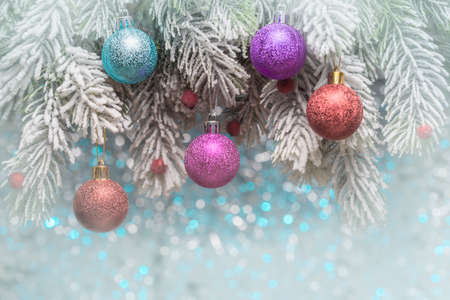 Christmas balls on frosty fir-tree branches over holiday backgroundの写真素材