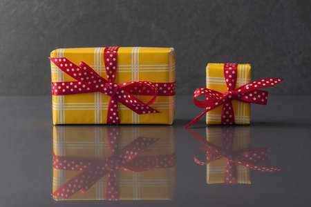 Two similar yellow gift boxes on grey stone backgroundの写真素材