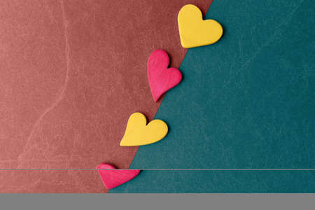 Valentineâs day background with pink and yellow hearts on colored stone surfaceの写真素材