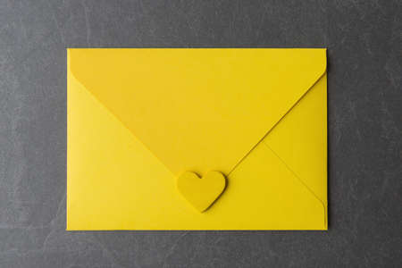 Yellow envelope and heart on grey background. Trendy Valentine âs Day greetingの写真素材