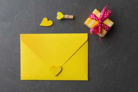 Yellow envelope, gift box and decorative Valentineâs hearts on dark grey backgroundの写真素材