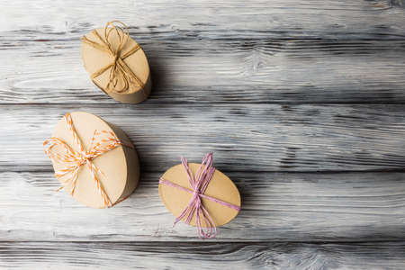Craft oval gift boxes on vintage stylized wooden background with copy space. Homemade Easter gifts