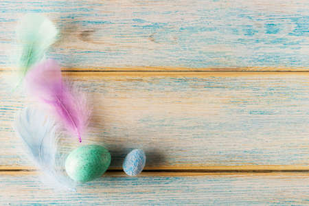 Decorative Easter eggs and feathers on wooden background with copy spaceの写真素材