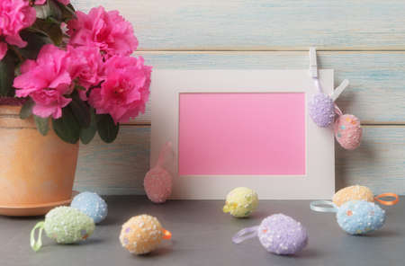 Easter greeting concept with decorative eggs, blank card in white frame and flowersの写真素材