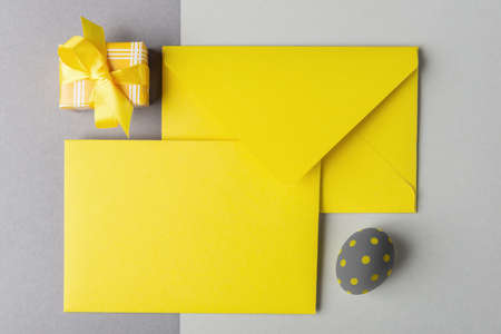 Yellow envelope with blank card, decorative egg and gift box on grey backgroundの写真素材