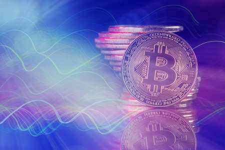 Close up of metal bitcoins stack against techno abstract background