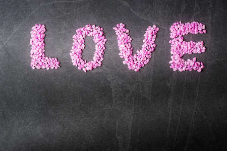Word Love made of pink tocks on grey stone background with copy space. Valentineâs day greeting conceptの写真素材