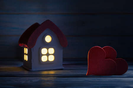 Two Valentineâs hearts over toy house at twilight. Valentines day greeting concept. Selective focus on heartsの写真素材