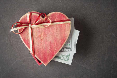 100 USD banknotes in heart shaped gift box over grey stone background. Love and money conceptの写真素材