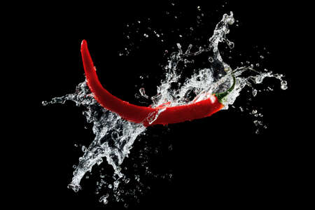 Red hot peppers in water splash over black backgroundの写真素材