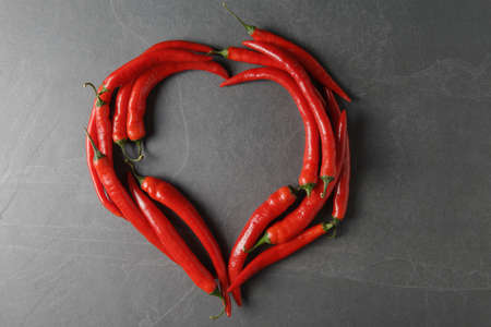 Red hot peppers arranged in a heart shape over grey stone backgroundの写真素材
