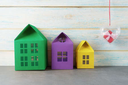 Three multicolored houses and a red gift box in a heart-shaped containerの写真素材