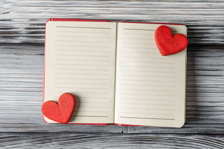 Open notebook with blank pages and red Valentines hearts on wooden backgroundの写真素材