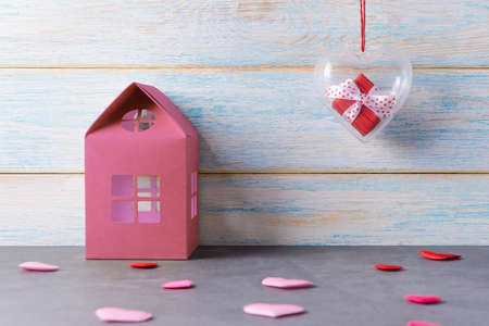 Toy house and hanging gift box over blue wooden background. Valentineâs day conceptの写真素材