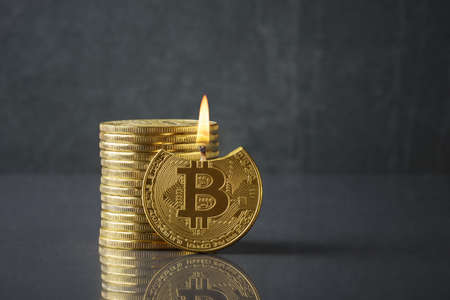 Bitcoin as a burning candle over dark background with copy space. Cryptocurrency risk conceptの写真素材