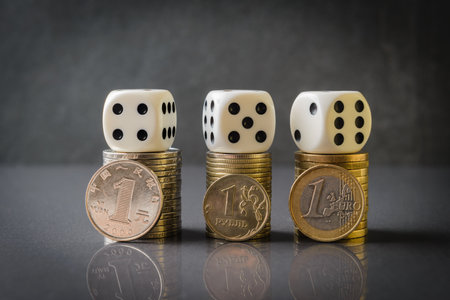 Euro, Yuan and Rubble coin stacks with dice over dark background. The idea of current economic problems and sanctionsの写真素材
